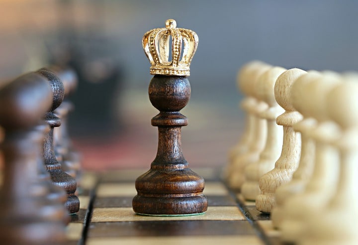 chess pawn in the middle of a chessboard wearing a crown
