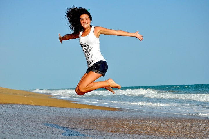 woman on beach jumping happy